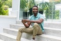 Portrait of smiling african american young man having coffee while sitting on steps outside house Royalty Free Stock Photo