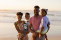 Portrait of smiling african american young parents carrying son and daughter against sea and sky Royalty Free Stock Photo