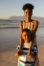 Portrait of smiling african american young woman holding son\'s hands against sea and clear sky Royalty Free Stock Photo