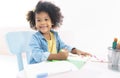 Portrait of smiling african girl sitting at desk in living room and looking at camera while drawing at home.New normal.Covid-19 Royalty Free Stock Photo