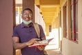 Portrait of a smiling African male student holding a book and smiling Royalty Free Stock Photo