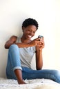 Smiling african woman relaxing at home and looking at smart phone