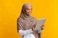 Portrait of smiling afro muslim girl in hijab using digital tablet