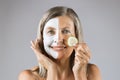 Aged woman with mask on face holding slice of cucumber Royalty Free Stock Photo