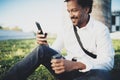 Portrait of Smiling American African man in headphone taking brake at sunny park with coffee in take away cup and Royalty Free Stock Photo