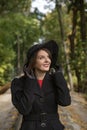 Portrait of smiling aristocratic woman in black hat with veil, in autumn park. Middle-aged woman in vintage retro style