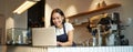 Portrait of smiling asian barista, cafe owner entrepreneur, working on laptop, processing orders on computer, standing Royalty Free Stock Photo