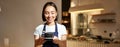 Portrait of smiling asian barista, girl in uniform, serving coffee, waitress holding cup of drink, working in cafe Royalty Free Stock Photo