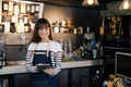 Portrait of smiling asian barista holding digital tablet at counter in coffee shop. Cafe restaurant service, food and drink indus Royalty Free Stock Photo