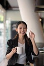 portrait smiling asian business woman pointing up and looking at the camera in modern office Royalty Free Stock Photo