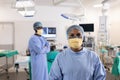 Portrait of smiling asian female surgeon in operating theatre with diverse colleague, copy space Royalty Free Stock Photo