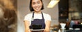 Portrait of smiling asian girl barista, waitress in cafe uniform, giving you cup of coffee, prepare drink for client Royalty Free Stock Photo
