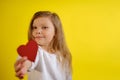Portrait of kid girl holding a red heart for you, isolated on yellow background with copy space. V3 Royalty Free Stock Photo