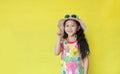 Portrait of smiling asian little child girl wearing a floral pattern summer dress and hat with sunglasses pointing up with copy Royalty Free Stock Photo