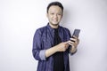 A Portrait Of A Smiling Asian Man Is Smiling And Holding His Smartphone Wearing A Navy Blue Shirt  By A White Background