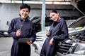 Portrait of smiling Asian mechanic man and beautiful woman in uniform standing, holding spanner at garage vehicle shop, auto Royalty Free Stock Photo