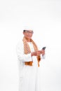 Portrait of smiling asian muslim old man wear white clothes using smartphone isolated over white Royalty Free Stock Photo
