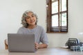 Portrait of smiling asian senior mature middle aged businesswoman using laptop working and web surfing on desk. Royalty Free Stock Photo