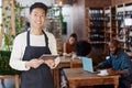 Portrait of smiling asian small business owner in his restaurant holding a wireless digital tablet. Young businessman Royalty Free Stock Photo