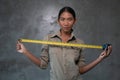 Portrait of smiling Asian woman architect holding measuring tape over concrete wall Royalty Free Stock Photo