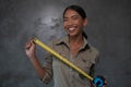 Portrait of smiling Asian woman architect holding measuring tape over concrete wall Royalty Free Stock Photo