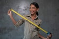 Portrait of smiling Asian woman architect holding measuring tape over concrete wall Royalty Free Stock Photo