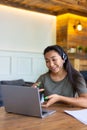 Portrait of a smiling asian woman with headset in front of laptop monitor. Royalty Free Stock Photo