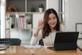 Portrait of smiling asian woman waving hello talking on video call. Successful young woman sitting white suits. Business