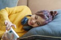 Portrait of a smiling Asian woman wearing a pair of headphones and using her phone and listening to music while sitting Royalty Free Stock Photo