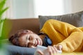 Portrait of a smiling Asian woman wearing a pair of headphones and using her phone and listening to music while sitting Royalty Free Stock Photo