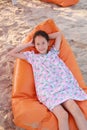 Portrait of smiling Asian young girl relax on sofa bed beach on sand at summer holiday Royalty Free Stock Photo