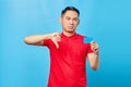 Portrait of smiling Asian young man holding credit card and showing thumbs down gesture on blue background Royalty Free Stock Photo