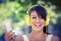 Portrait of smiling athletic woman wearing yellow headphones and holding smartphone