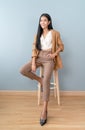 Portrait of smiling an attractive Asian businesswoman waring brown suit cool chic while sitting on chair and looking at camera Royalty Free Stock Photo