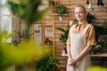 Portrait of smiling attractive female florist wearing apron standing posing in floral shop, looking at camera. Royalty Free Stock Photo