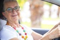 Portrait of a smiling attractive senior woman with eyeglasses enjoying drive her car. Travel and transportation concept