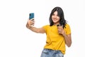 Portrait of a smiling attractive woman taking a selfie while holding take away coffee cup isolated over white background Royalty Free Stock Photo