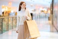 Portrait of smiling attractive young woman holding in hands shopping paper bags with purchase walking in mall with Royalty Free Stock Photo