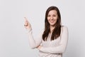 Portrait of smiling attractive young woman in light clothes pointing index finger aside up on white wall Royalty Free Stock Photo