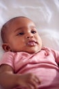 Portrait Of Smiling Baby Girl Lying On Parents Bed In Bedroom Royalty Free Stock Photo