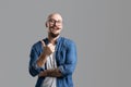 Portrait of a smiling balded bearded with mustache man in glasses showing thumb up over gray background