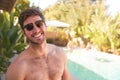 Portrait Of Smiling Bare Chested Man Wearing Sunglasses Outdoors With Friends At Summer Pool Party