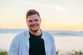 portrait of smiling beard man sunrise in mountains on background