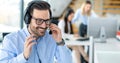 Portrait of smiling bearded call center operator man sitting at workplace. Call center concept. Royalty Free Stock Photo