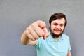 Portrait of smiling bearded man pointing finger at camera on gray background. Focus on finger Royalty Free Stock Photo