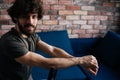 Portrait of confident bearded young man looking at camera sitting on chair and holding to chairbac in cozy living room Royalty Free Stock Photo