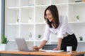 Portrait of smiling beautiful Asian businesswoman enjoy the idea sitting with laptop computer at office. Royalty Free Stock Photo