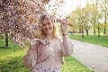 Portrait of smiling beautiful blonde hair woman in pink knitted cardigan holding branches of blooming lilac on sunny day Royalty Free Stock Photo