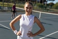 Portrait of smiling beautiful caucasian female tennis player standing with hands on hip at court Royalty Free Stock Photo