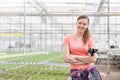 Portrait of smiling beautiful female botanist standing with arms crossed against herbs in greenhouse